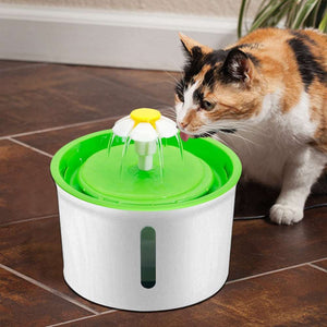 a cat drinking water from a green cup 