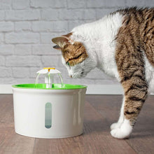 a cat drinking water from a green cup 